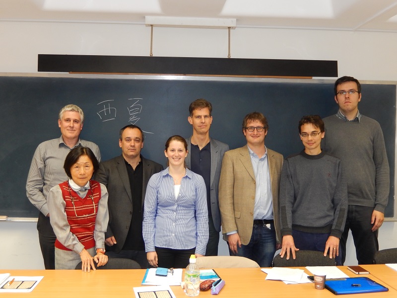 Photograph of a group of eight people standing in front of a blackboard